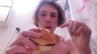 Nude damsel munches burger while on the rest room