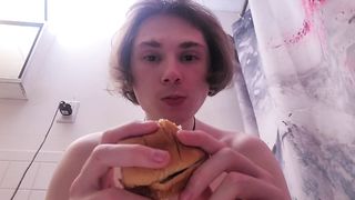 Nude damsel munches burger while on the rest room